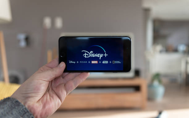 a person holding a phone disneyplus.com login/begin